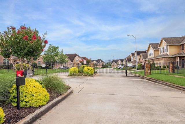 18621 Serenity Loch Dr, Spring, TX 77379 - view of concrete street featuring a residential view, curbs, street lights, a gate, and a gated entry