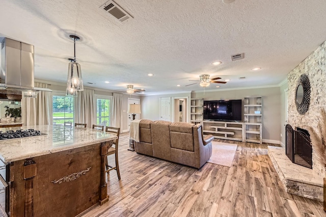 29742 Geneva Dr, Spring, TX 77386 - living area featuring light wood-style flooring, ornamental molding, a ceiling fan, a textured ceiling, and a stone fireplace