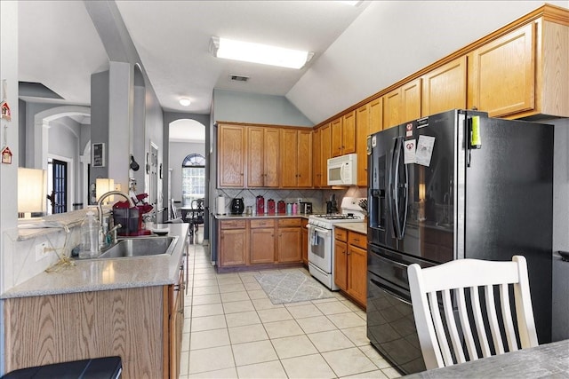 8511 Silver Lure Dr, Humble, TX 77346 - kitchen featuring white appliances, arched walkways, light tile patterned floors, lofted ceiling, and decorative backsplash