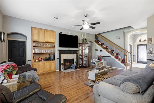 8511 Silver Lure Dr, Humble, TX 77346 - living room with ceiling fan, a tile fireplace, stairway, and light wood-style floors