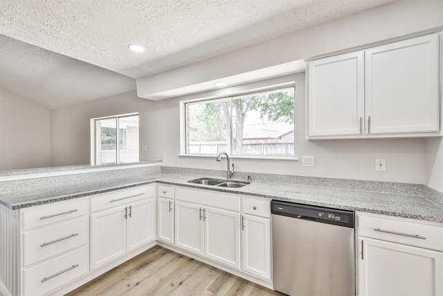 23203 Pennsgrove Rd, Spring, TX 77373 - kitchen with stainless steel dishwasher, a sink, light wood-style flooring, a textured ceiling, and white cabinets