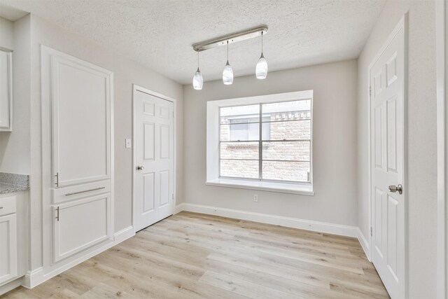 23203 Pennsgrove Rd, Spring, TX 77373 - unfurnished dining area featuring light wood-type flooring, a textured ceiling, and baseboards