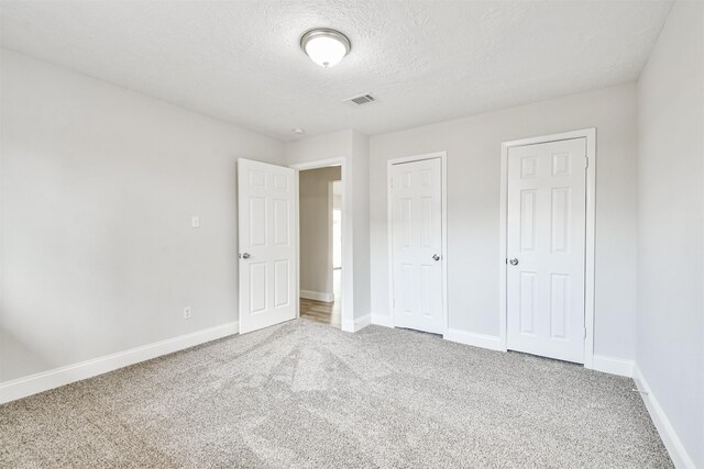23203 Pennsgrove Rd, Spring, TX 77373 - unfurnished bedroom with carpet floors, baseboards, a textured ceiling, and two closets