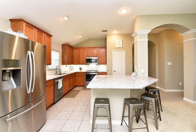 711 Shenandoah Falls Ln, Rosenberg, TX 77469 - kitchen with appliances with stainless steel finishes, a sink, ornate columns, a breakfast bar, and light stone countertops