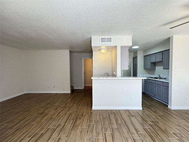 6500 Sands Point Dr Unit 114, Houston, TX 77074 - kitchen with wood finish floors, a textured ceiling, a sink, light countertops, and baseboards