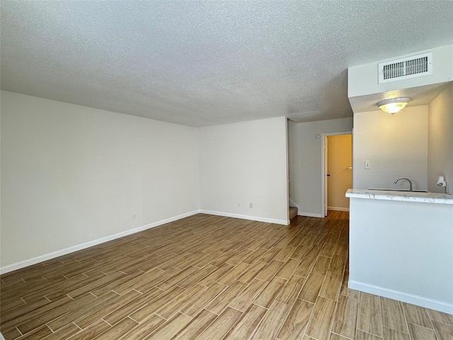 6500 Sands Point Dr Unit 114, Houston, TX 77074 - unfurnished living room featuring light wood finished floors, baseboards, and a textured ceiling