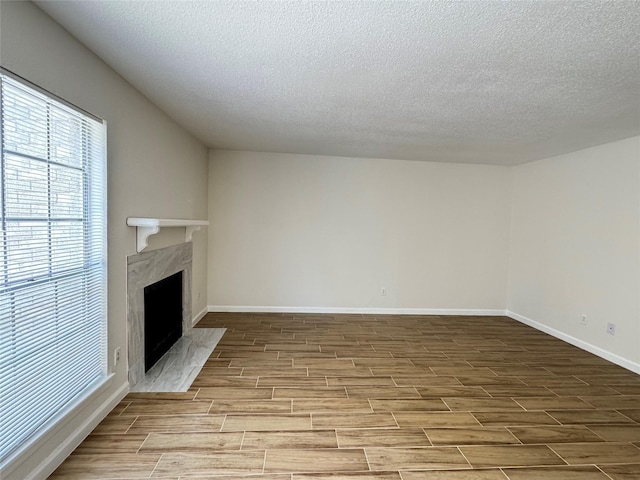 6500 Sands Point Dr Unit 114, Houston, TX 77074 - unfurnished living room with wood finished floors, a high end fireplace, a textured ceiling, and baseboards