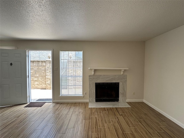 6500 Sands Point Dr Unit 114, Houston, TX 77074 - unfurnished living room with wood finish floors, a premium fireplace, baseboards, and a textured ceiling