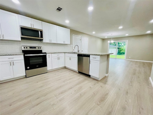 105 Cornelia St, Sweeny, TX 77480 - kitchen featuring stainless steel appliances, light wood-style floors, decorative backsplash, a sink, and a peninsula