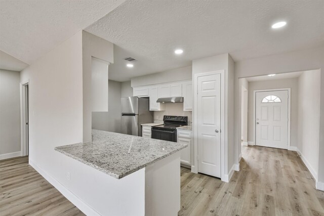12523 Drifting Winds Dr, Houston, TX 77044 - kitchen with black / electric stove, freestanding refrigerator, light wood finished floors, under cabinet range hood, and white cabinetry