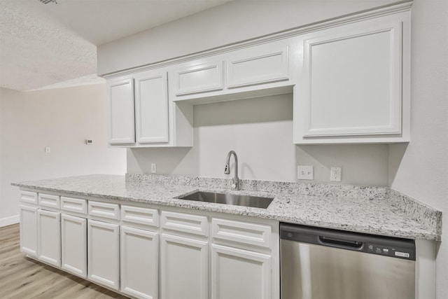 12523 Drifting Winds Dr, Houston, TX 77044 - kitchen with dishwasher, a sink, light wood finished floors, a textured ceiling, and light stone countertops