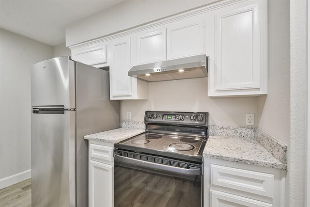 12523 Drifting Winds Dr, Houston, TX 77044 - kitchen featuring black electric range, under cabinet range hood, freestanding refrigerator, light wood-type flooring, and white cabinetry