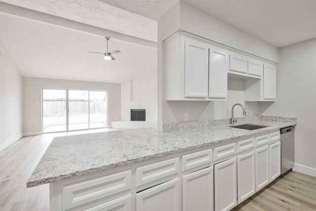 12523 Drifting Winds Dr, Houston, TX 77044 - kitchen featuring dishwasher, a sink, open floor plan, white cabinetry, and baseboards