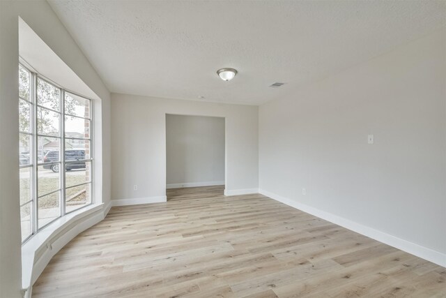 12523 Drifting Winds Dr, Houston, TX 77044 - unfurnished room with plenty of natural light, light wood-type flooring, baseboards, and a textured ceiling
