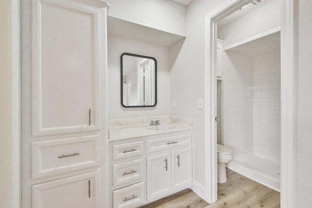 12523 Drifting Winds Dr, Houston, TX 77044 - full bathroom with toilet, vanity, wood finished floors, and a tile shower