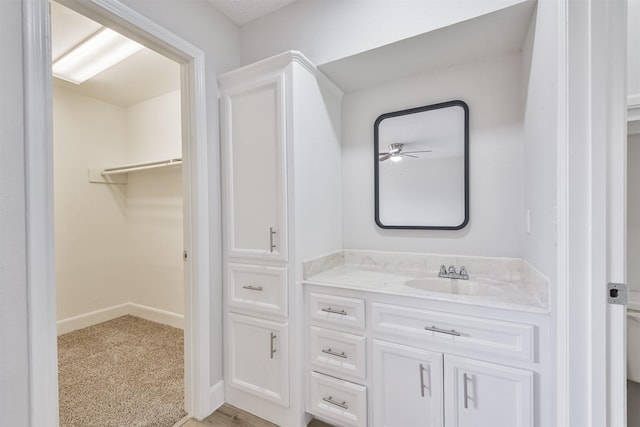 12523 Drifting Winds Dr, Houston, TX 77044 - bathroom with vanity, a ceiling fan, a spacious closet, and baseboards