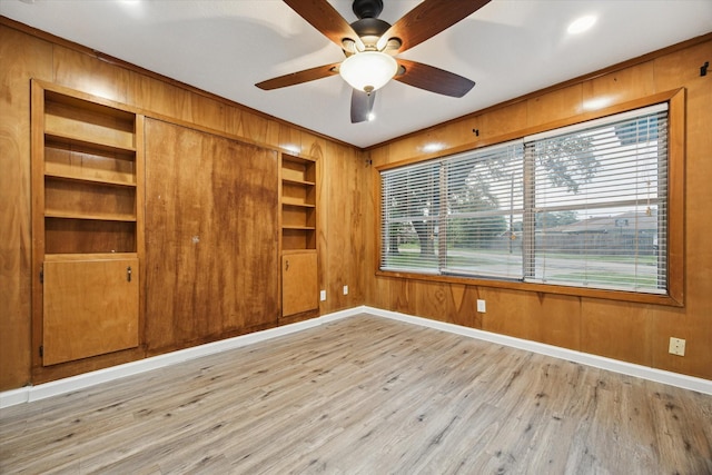 1301 Gulf St, Pasadena, TX 77502 - empty room with wood walls, baseboards, light wood-type flooring, a ceiling fan, and ornamental molding