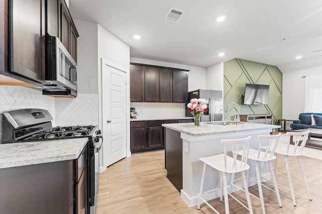 818 Deerhurst Ln, Magnolia, TX 77354 - kitchen with stainless steel appliances, tasteful backsplash, dark brown cabinetry, light countertops, and light wood finished floors