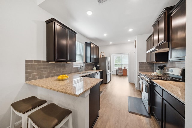 6006 Hazel Place Dr, Conroe, TX 77303 - kitchen featuring stainless steel appliances, a sink, light stone counters, light wood-type flooring, and recessed lighting