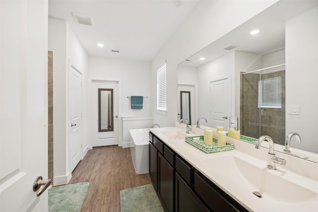 6006 Hazel Place Dr, Conroe, TX 77303 - bathroom with a stall shower, double vanity, a soaking tub, wood finished floors, and recessed lighting