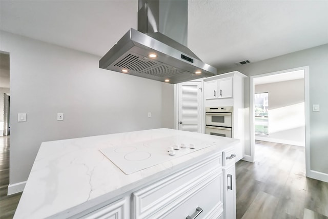 3522 Creekbriar Dr, Houston, TX 77068 - kitchen with wall chimney range hood, white appliances, dark wood-type flooring, light stone counters, and white cabinetry