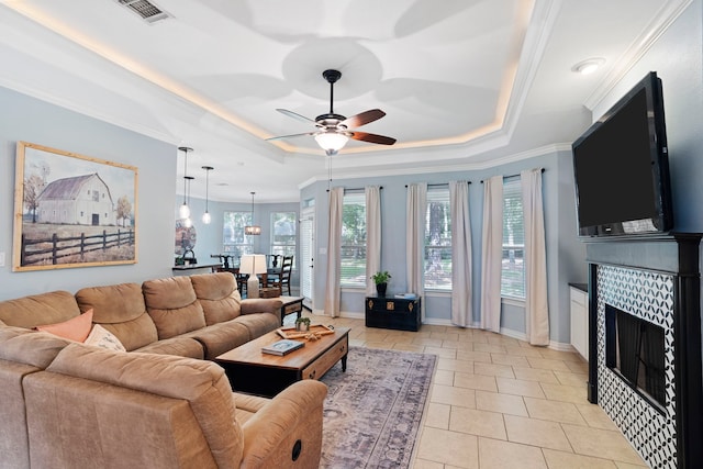 15 Rose Pine Ct, Magnolia, TX 77355 - living room with ceiling fan, a tray ceiling, a tiled fireplace, ornamental molding, and baseboards