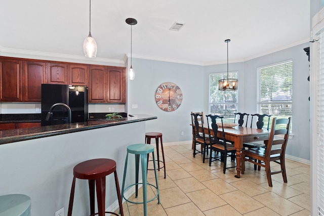 15 Rose Pine Ct, Magnolia, TX 77355 - kitchen featuring freestanding refrigerator, crown molding, a kitchen bar, decorative light fixtures, and light tile patterned floors
