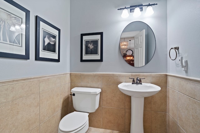 15 Rose Pine Ct, Magnolia, TX 77355 - bathroom with tile walls, toilet, wainscoting, and a sink