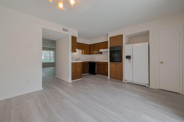6103 Fondren Rd Unit 7, Houston, TX 77036 - kitchen with black appliances, light countertops, light wood-style floors, brown cabinets, and under cabinet range hood