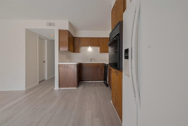 6103 Fondren Rd Unit 7, Houston, TX 77036 - kitchen with black appliances, light wood-style flooring, brown cabinets, a sink, and baseboards