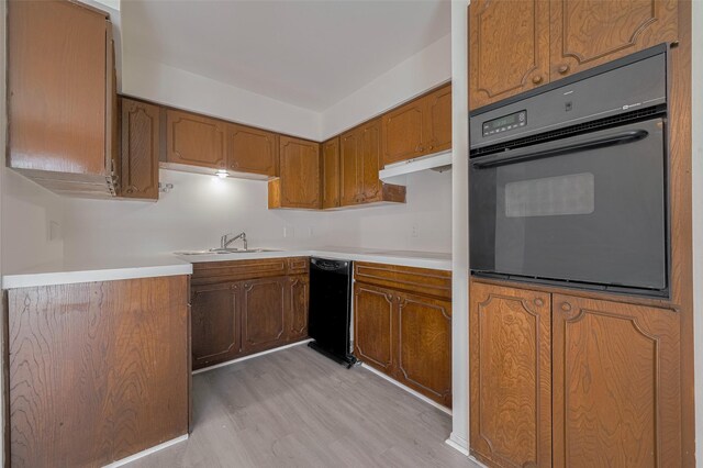 6103 Fondren Rd Unit 7, Houston, TX 77036 - kitchen featuring black appliances, a sink, brown cabinets, light wood-style flooring, and light countertops