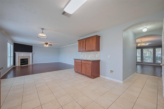5011 Bridgecrossing Ct, Spring, TX 77379 - kitchen with a ceiling fan, light tile patterned floors, a textured ceiling, brown cabinetry, and arched walkways