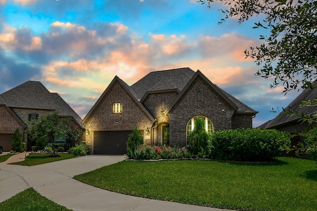 2334 Twin Rose Dr, Missouri City, TX 77459 - french country style house featuring brick siding, driveway, a front lawn, a shingled roof, and a garage