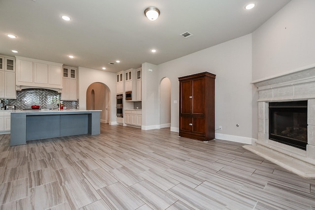 2334 Twin Rose Dr, Missouri City, TX 77459 - kitchen with open floor plan, arched walkways, decorative backsplash, light countertops, and a kitchen island with sink