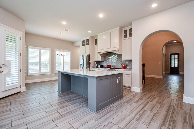 2334 Twin Rose Dr, Missouri City, TX 77459 - kitchen featuring stainless steel fridge, decorative backsplash, baseboards, arched walkways, and light wood-style flooring