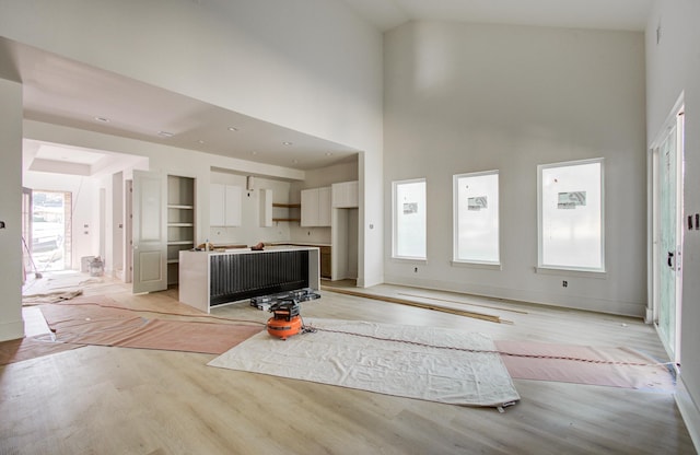1802 Rollingwood Dr, Huntsville, TX 77340 - living area featuring light wood finished floors, a towering ceiling, and baseboards