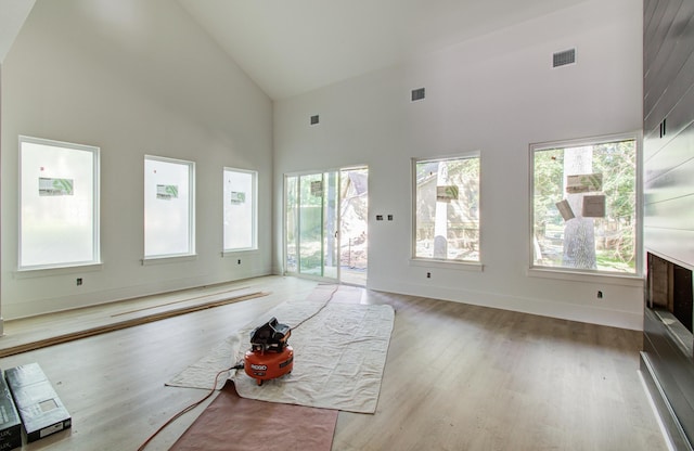 1802 Rollingwood Dr, Huntsville, TX 77340 - unfurnished living room with high vaulted ceiling, plenty of natural light, light wood-style floors, and baseboards