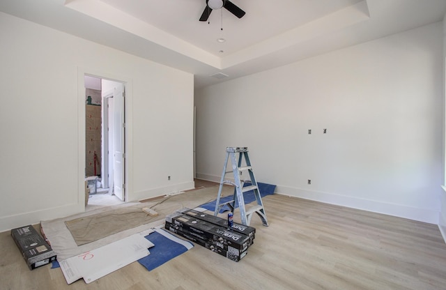 1802 Rollingwood Dr, Huntsville, TX 77340 - workout room with a tray ceiling, a ceiling fan, baseboards, and light wood-style floors