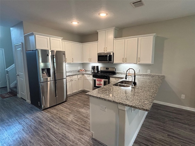1404 Rd 5102, Cleveland, TX 77327 - kitchen with stainless steel appliances, a sink, a peninsula, white cabinets, and dark wood-style flooring