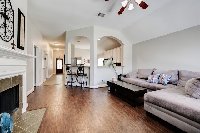 26622 Clear Mill Ln, Katy, TX 77494 - living area with a ceiling fan, dark wood-style flooring, a tile fireplace, baseboards, and arched walkways