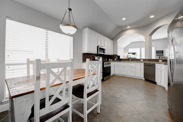 26622 Clear Mill Ln, Katy, TX 77494 - kitchen featuring stainless steel appliances, arched walkways, white cabinetry, vaulted ceiling, and light tile patterned floors