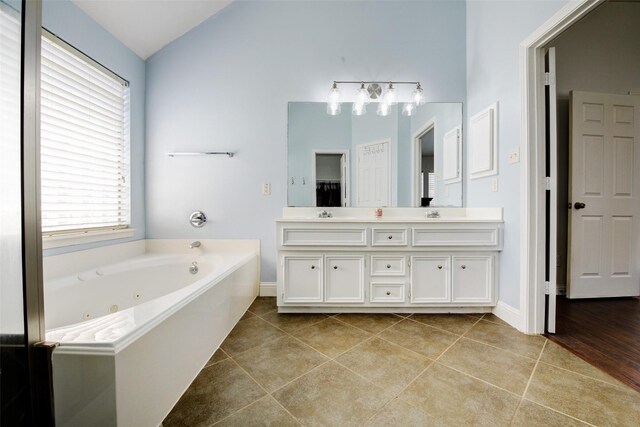 26622 Clear Mill Ln, Katy, TX 77494 - bathroom featuring double vanity, a tub with jets, lofted ceiling, tile patterned flooring, and baseboards