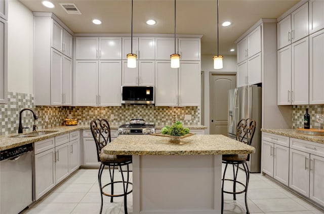 6710 Woodbend Park S, Houston, TX 77055 - kitchen featuring appliances with stainless steel finishes, a sink, light tile patterned floors, a kitchen island, and decorative backsplash