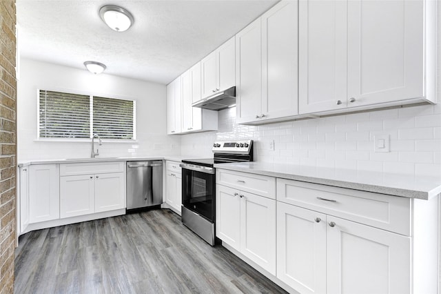 1323 Fieldstone, Missouri City, TX 77489 - kitchen with appliances with stainless steel finishes, under cabinet range hood, a sink, a textured ceiling, and tasteful backsplash