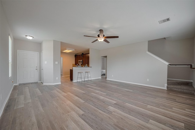 2810 Meadowbrook Ln, Rosenberg, TX 77471 - unfurnished living room featuring ceiling fan, baseboards, light wood-style floors, and stairway