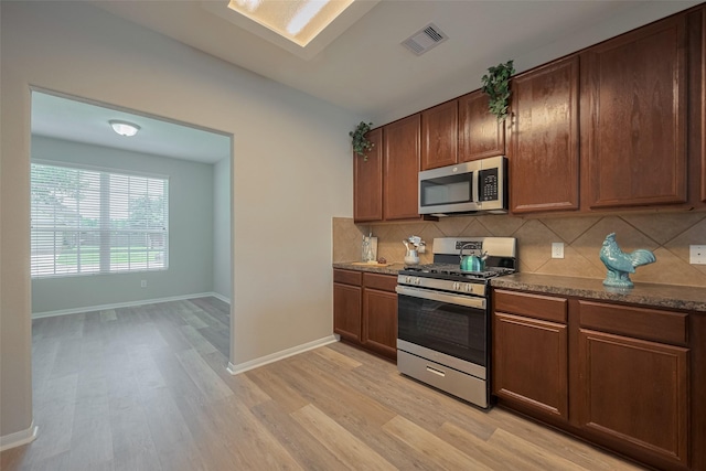 2810 Meadowbrook Ln, Rosenberg, TX 77471 - kitchen featuring appliances with stainless steel finishes, light wood-type flooring, backsplash, and baseboards
