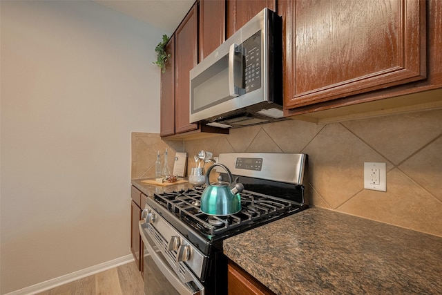 2810 Meadowbrook Ln, Rosenberg, TX 77471 - kitchen with stainless steel appliances, dark countertops, tasteful backsplash, and light wood finished floors