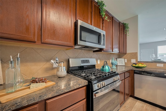 2810 Meadowbrook Ln, Rosenberg, TX 77471 - kitchen featuring stainless steel appliances, light wood-style floors, dark stone countertops, and brown cabinetry