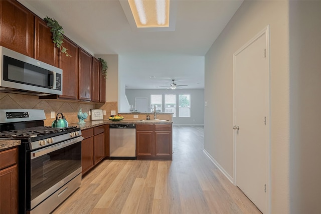 2810 Meadowbrook Ln, Rosenberg, TX 77471 - kitchen with appliances with stainless steel finishes, light wood-type flooring, a sink, a peninsula, and decorative backsplash