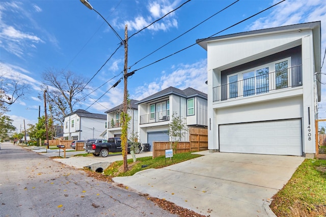 4908 Broom St, Houston, TX 77091 - view of front of property featuring a garage, concrete driveway, stucco siding, a residential view, and a balcony